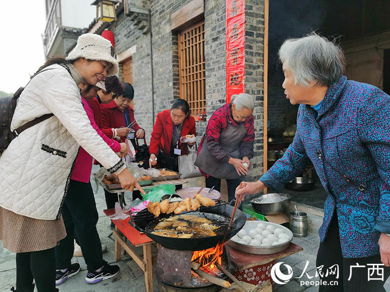 柳州市民在鱼峰区白沙镇集市购买当地特色小吃。人民网 付华周摄