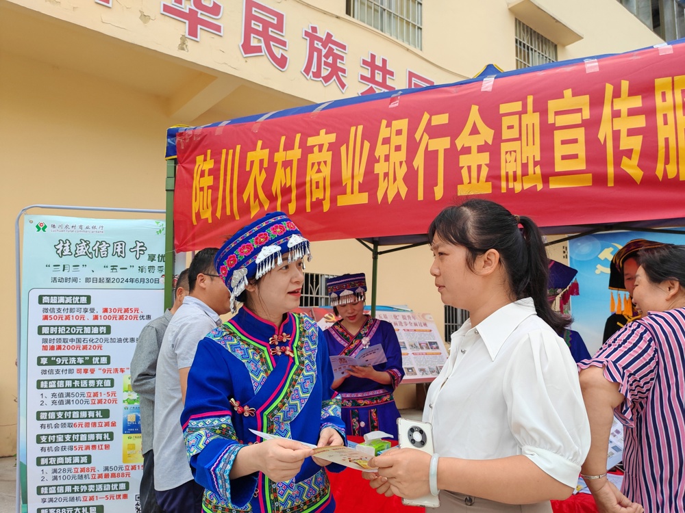 图为陆川农商银行工作人员身着民族服饰在陆川县温泉镇洞心村进行金融知识宣传 陆川农商银行供图